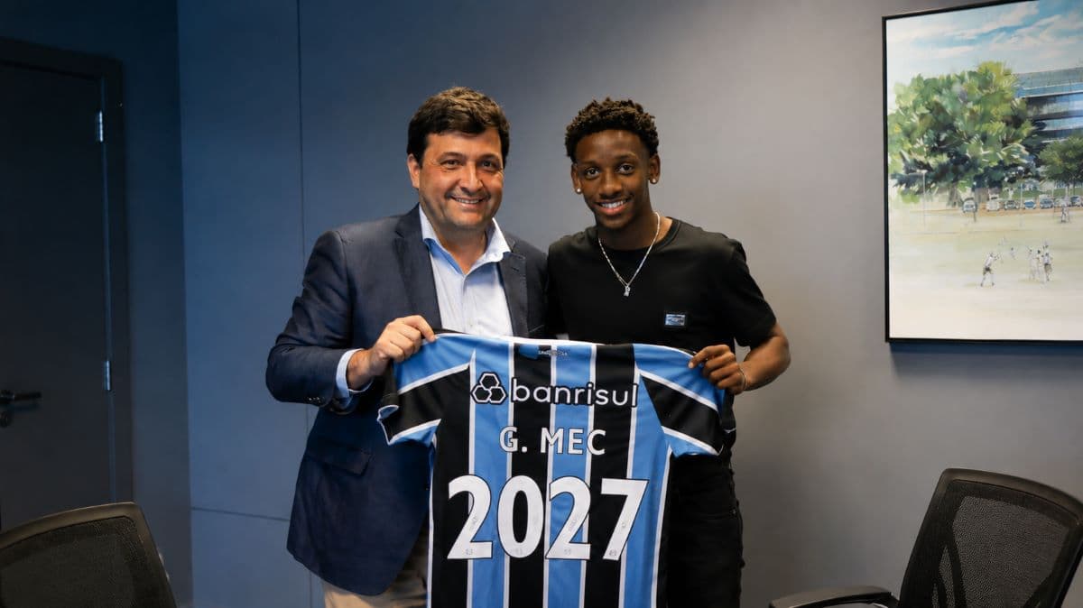 Gabriel Mec holding a Gremio shirt reading G. Mec 2027 alongside a club official